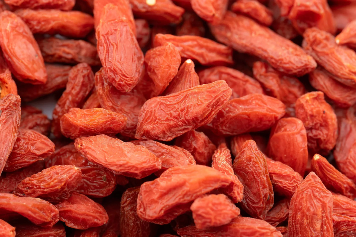 Close-up of dried goji berries in reddish-orange shades, showing their elongated shapes and naturally wrinkled surfaces.