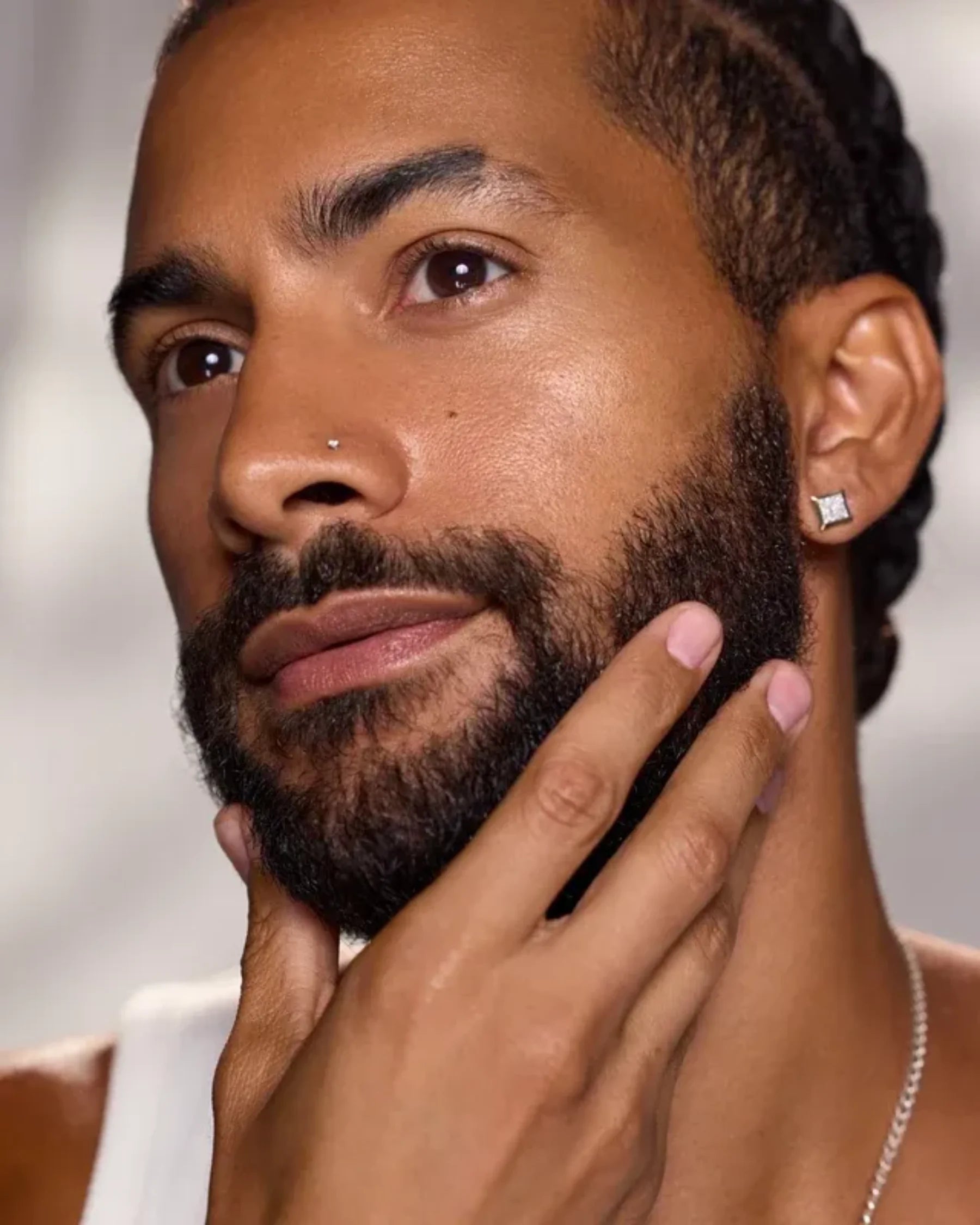 Model massaging facial oil into the beard and skin as part of a skincare routine
