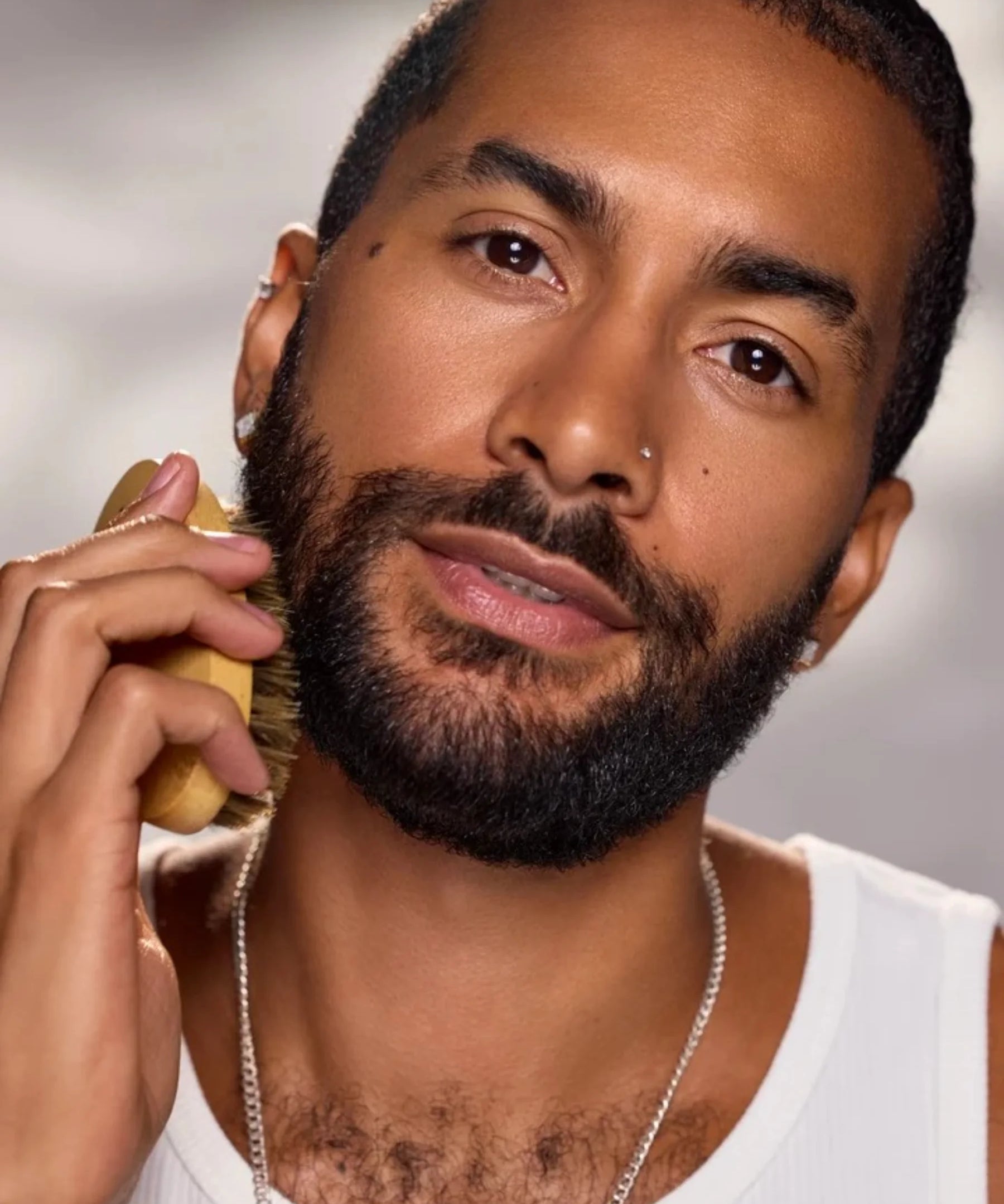 Model grooming his beard with a beard brush for a healthy, well-conditioned beard