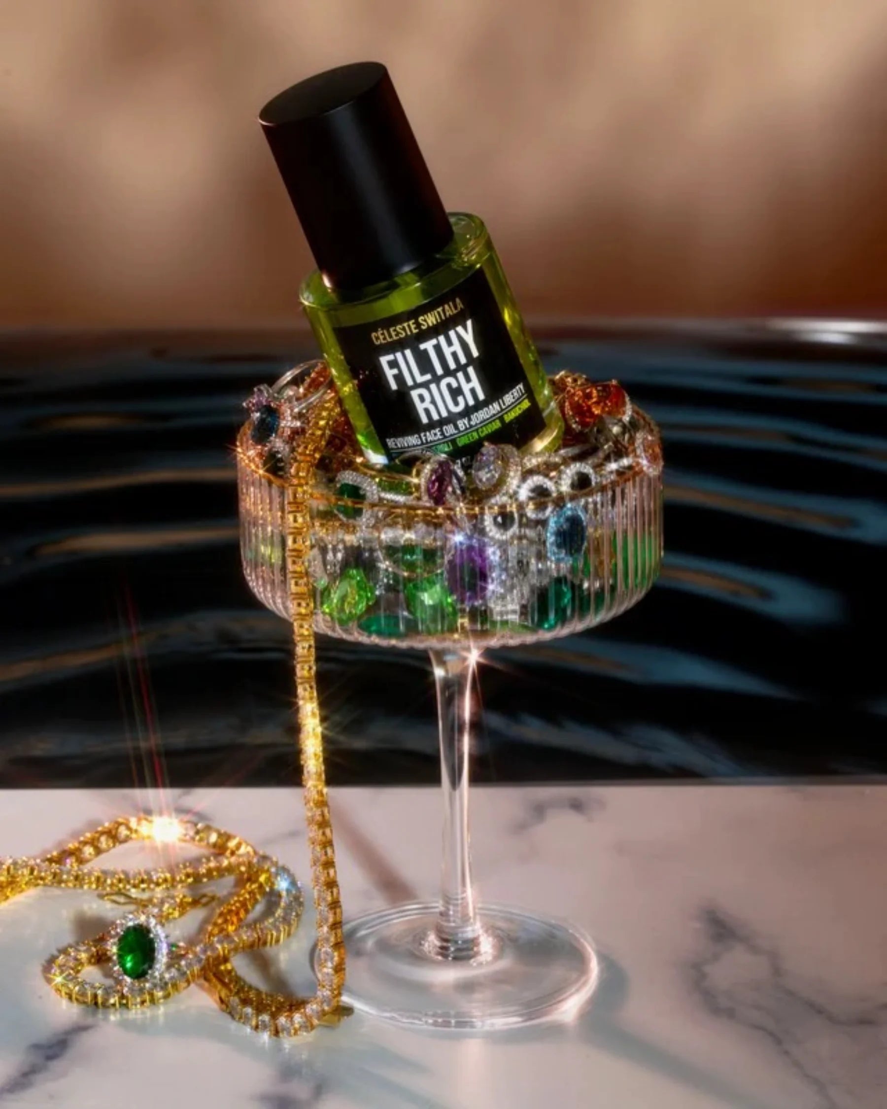 Filthy Rich Reviving Face Oil displayed with colorful luxury jewelry