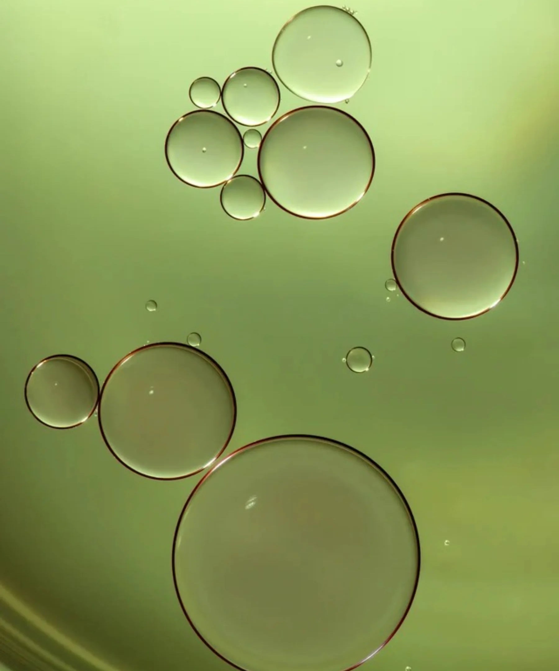 Macro view of golden green oil droplets representing Filthy Rich Reviving Face Oil texture