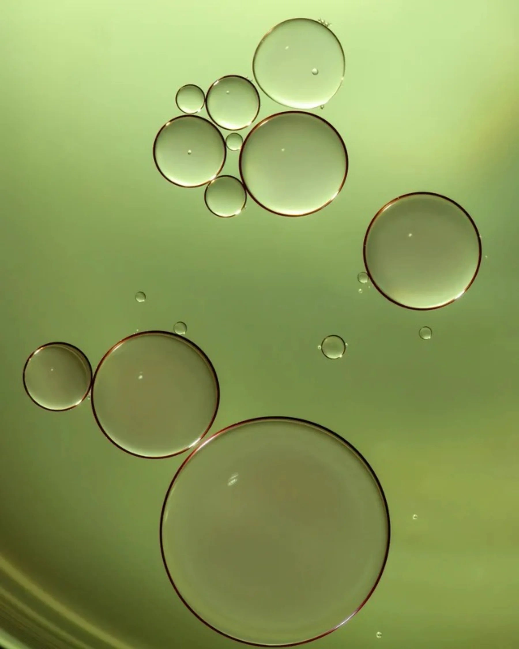Macro view of golden green oil droplets representing Filthy Rich Reviving Face Oil texture