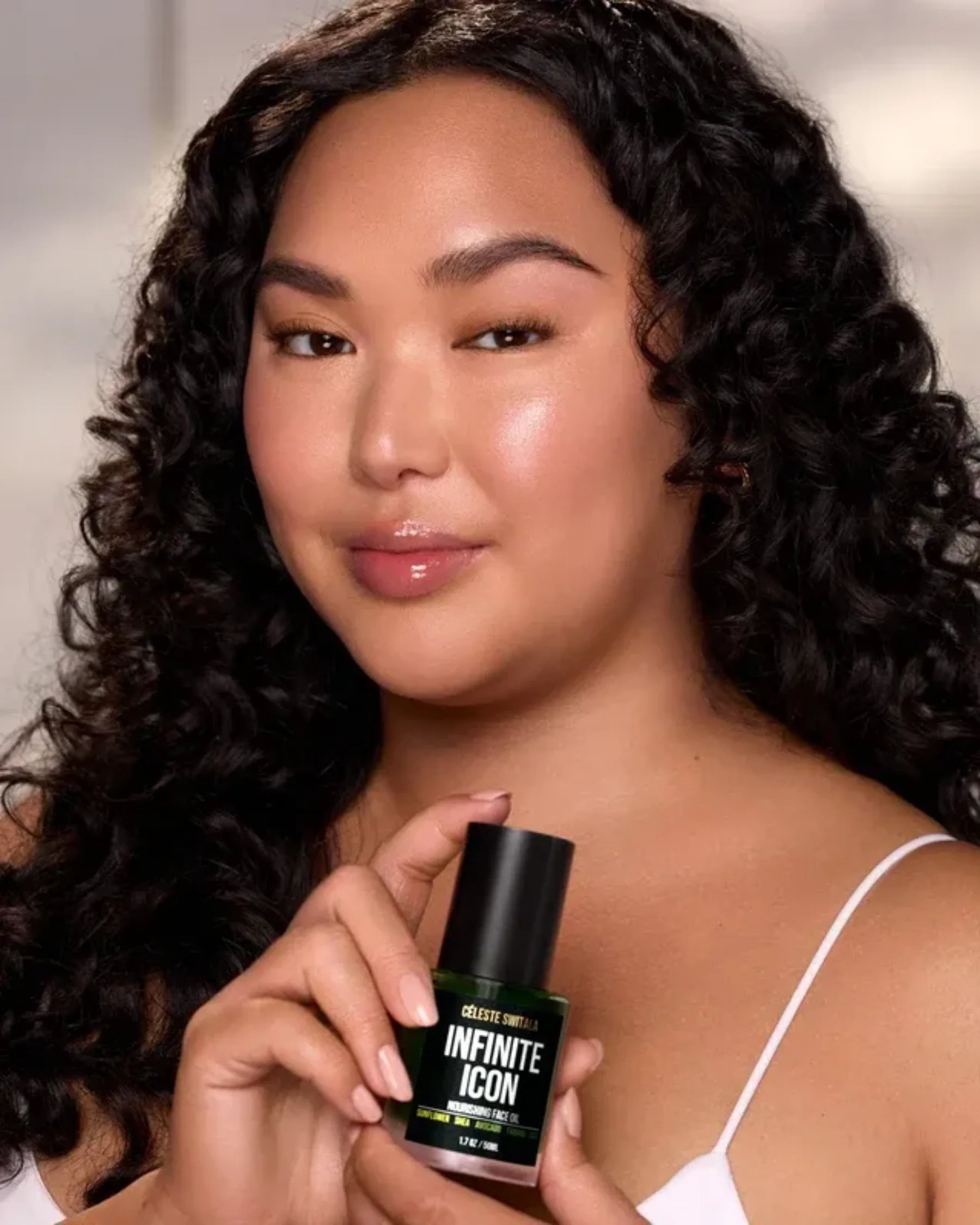 Model holding Infinite Icon Nourishing Face Oil by Céleste Switala