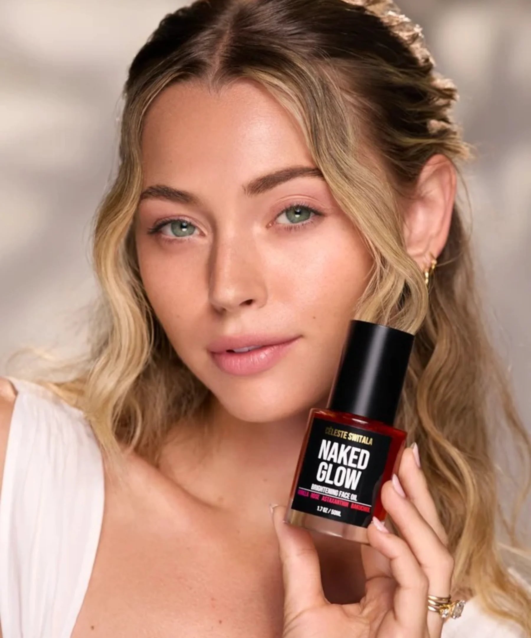 Woman holding Céleste Switala Naked Glow Brightening Face Oil beside her face