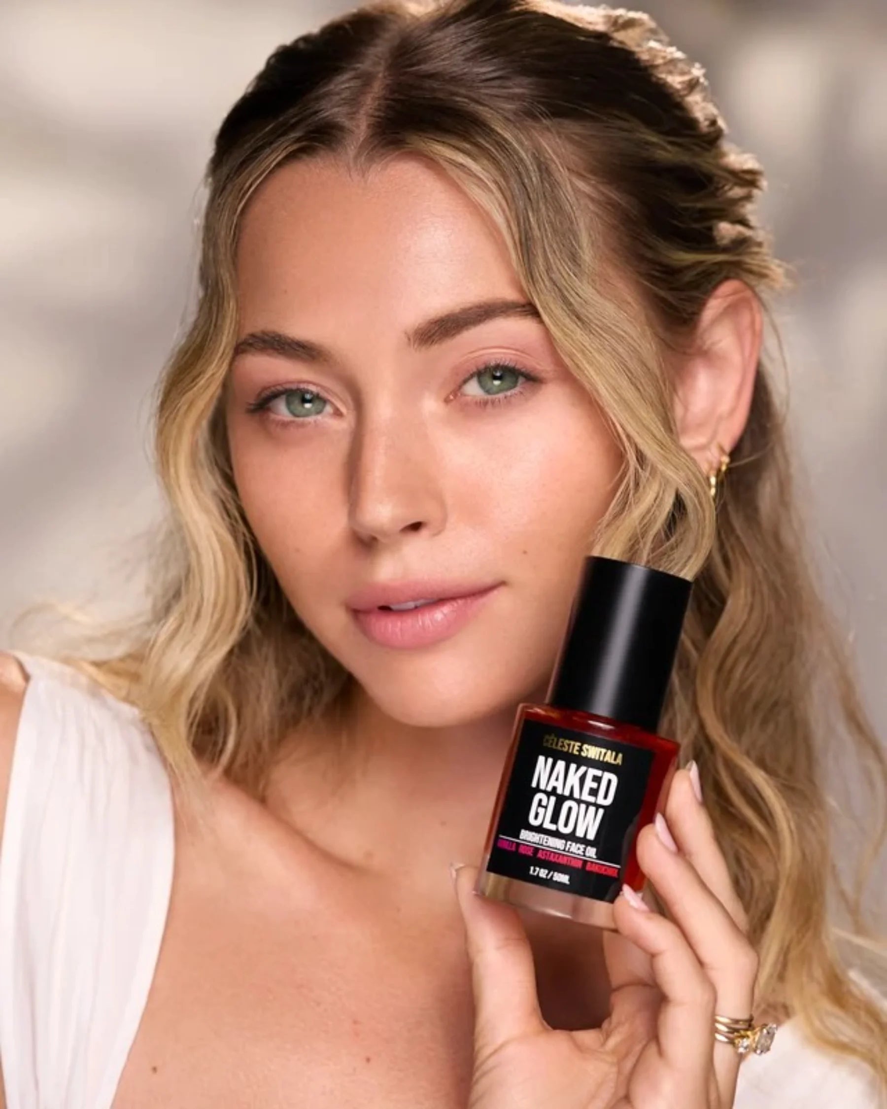 Woman holding Céleste Switala Naked Glow Brightening Face Oil beside her face